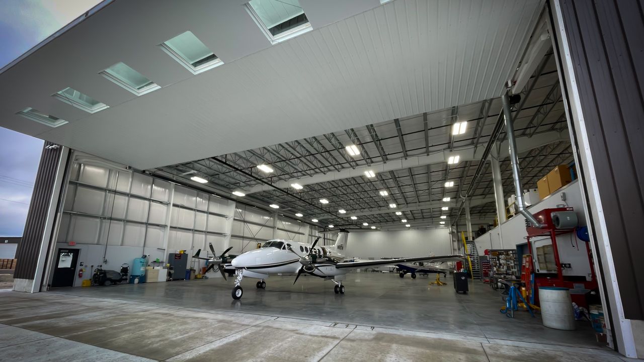 A turboprop parked inside a brightly lit maintenance hangar